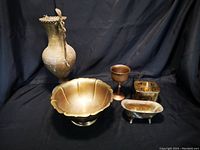 Photo showing all five tarnished brass items including flower holder, goblet, soap dish, bowl, and reindeer-design box