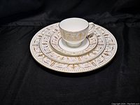 Stacked dinner plate, dessert plate, saucer and cup on black fabric backdrop illustrating pattern