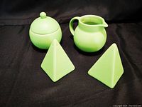 All four green kitchenware items shown on a black background: covered sugar bowl, creamer, salt and pepper shakers