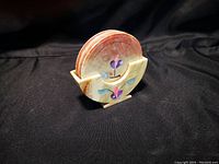 Photo showing six round soapstone coasters in a matching soapstone holder with floral inlay design on both coasters and holder.