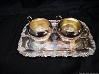 Photo of silver plated Rogers creamer and covered sugar bowl on ornate Old English style silver tray