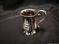 Photo of a small sterling silver mini pitcher with ornate floral designs and curved handle