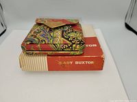 Vintage Lady Buxton compact resting on its original Lady Buxton box, showcasing colorful paisley/floral pattern and box details.