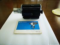 Kodak Model 1201 8mm movie camera with user manual on white background