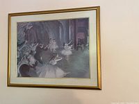 Framed ballerina painting hanging on a wall showing multiple ballerinas in a theater setting.