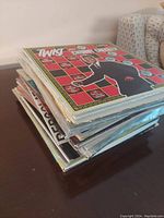 Stack of approximately 20 assorted vinyl records with colorful covers, top one featuring a man in a suit with a checkered background.