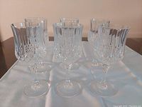 Photo showing six crystal sherry glasses with intricate cut glass pattern on a white cloth.