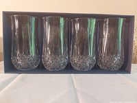 Set of four crystal highball glasses in original box, showing clear glass with a diamond cut base pattern.