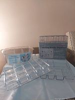 Clear plastic stacking jewelry organizer and divided cosmetic tray visible on a flat surface.