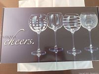 Box of Mikasa Cheers red wine glasses showing five different styles of glass designs including polka dots, vertical stripes, and horizontal stripes.