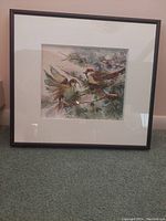 Framed watercolour artwork titled 'Greetings' by Joan Hopkins featuring two birds perched in pine branches, matted and in black frame.