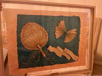Photo of framed art piece titled 'Stepping Out' showing textured dark green background with paper fan decorations and wood frame.
