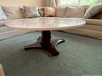 Full view of marble top coffee table showing the round polished white marble surface and dark wooden pedestal base with four feet.