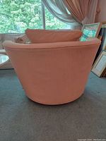 Rear view of the peach shell-shaped accent chair showing curved backrest and fabric upholstery.