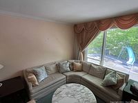 Photo showing a curved vintage fabric sectional sofa with multiple toss cushions in a living room setting.