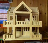 Front view of empty two-story wooden dollhouse with balcony and windows