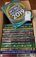 Box with 17 hardcover Guinness World Records books from 2000 to 2019 mostly in sequential order the spines visible for identification.