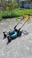 Side angle view of blue and black Yardworks corded electric lawn mower with orange extension cord wrapped on handlebar, showing wheels and body.