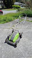 Greenworks electric lawnmower on driveway from front top angle showing handlebar and deck.
