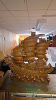 Photo of brown ceramic Asian theme model ship with detailed sails and dragon head in a basement setting.