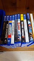 Ten PS4 games standing vertically showing spine titles, including Deus Ex Mankind Divided, For Honor, Lost Sphear, New Gundam Breaker, Destiny The Taken King, LEGO Jurassic World, Dragon Ball Xenoverse, Destiny 2, and two unidentified titles.