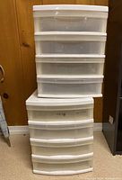 Front view of two plastic storage bins stacked, showing multiple drawers with white frames and clear fronts.