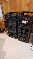 Two stacks of black plastic storage crates showing overall condition and design