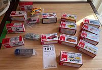 Overview of all Takara Tomy diecast cars including boxed and loose cars on a wooden surface showing variety and quantity