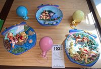 Three Winnie the Pooh Bradford Exchange collector plates depicting characters in colorful, detailed scenes and three pastel-colored ceramic balloon decorations.