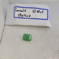 Image showing the emerald gemstone with label indicating its size 15x11x7mm and weight 10.10ct.