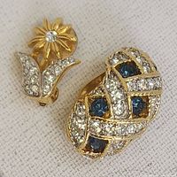 Two single vintage D'orlan clip-on earrings showing front detail, one floral and one with woven blue and clear rhinestones