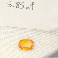 Overhead shot showing the orange sapphire alongside a handwritten note indicating 5.85ct weight.