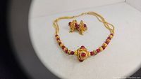 Photo showing the full necklace and earrings set with Byzantine revival style, ruby cabochons, red beryl beads, and gold-tone metal.