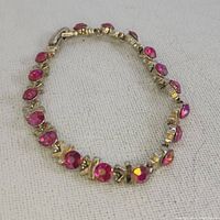 Image showing the full length of the vintage tennis bracelet laid flat, highlighting pink round rhinestones and gold-tone metal setting.