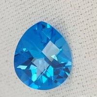 Top view of a brilliantly faceted pear shaped blue topaz gemstone showing cut and clarity.
