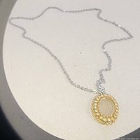 Full view of vintage cameo pendant hanging on white chain, showing overall length and design.