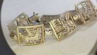 Close-up photo of the vintage bracelet showing the detailed design of rectangular panels with deer and hunt motifs.