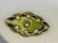 Front view of the vintage green enamel brooch with crystals, showing design and signature details.