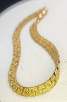 Close-up photo showing the textured nugget design and foldover clasp of the bracelet on a white cloth background.