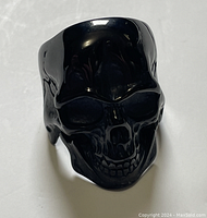 Front view of glossy black skull ring showing detailed facial features.