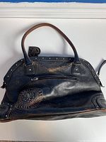 Back view of the Harley Davidson black leather bag showing zippered pocket and embossed logo