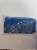 Blue heated back belt sealed inside clear plastic packaging, viewed from front.