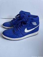 Side angle of the blue leather Nike Air Jordan 1 shoes showing the white Nike swoosh and Air Jordan wings logo.