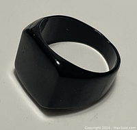 Black ring photographed from a side angle showing the thickness and rounded edges of the band.