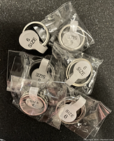 Photo of seven size 6 fidget rings individually packaged in small plastic bags, showing the spinner ring design.