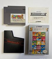 Photo showing NES cartridge with label, manual, black Nintendo sleeve, and original box front.