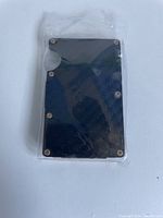 Front view of the sealed black carbon fiber wallet with metal rivets on the edges and a card access cutout.