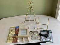 Eleven plate and picture frame holders of mixed material and style on a white table with light green background wall