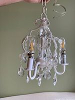 White chandelier ceiling light fixture with 3 light bulbs and crystal bead decorations.