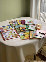 Overview of children's books, puzzles, and activity pads spread on a table with natural light from window